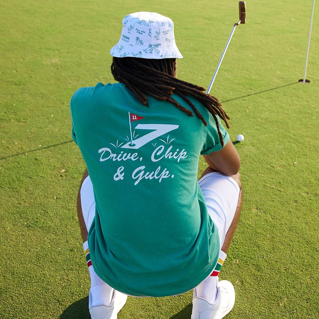 Man on a golf course wearing a green shirt that says "Drive, Chip, and Gulp"