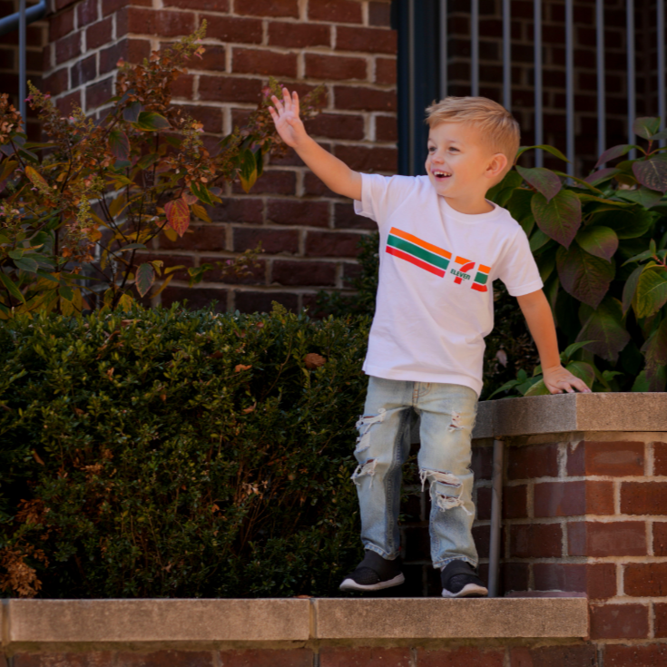 Child waving and wearing a 7-Eleven Classic Logo T-Shirt